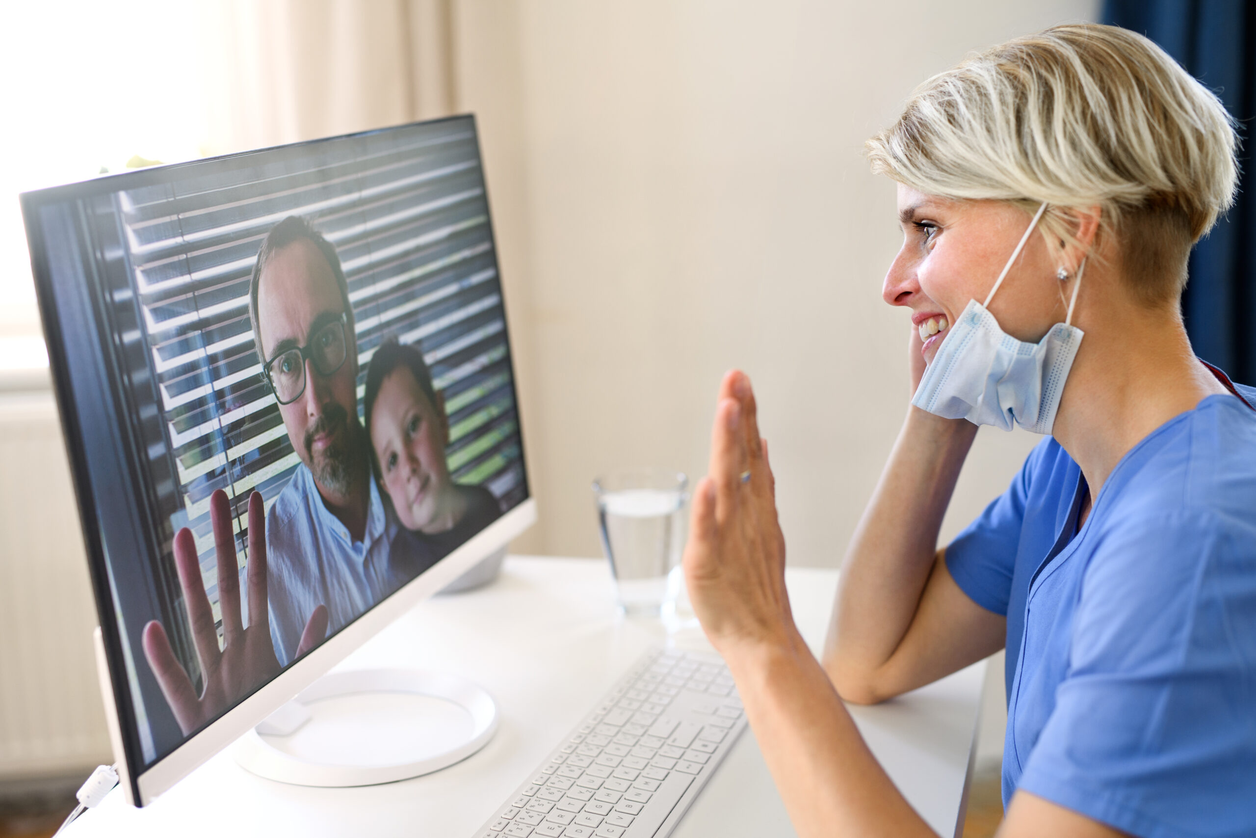 female medical professional speaking with man and boy over video conference